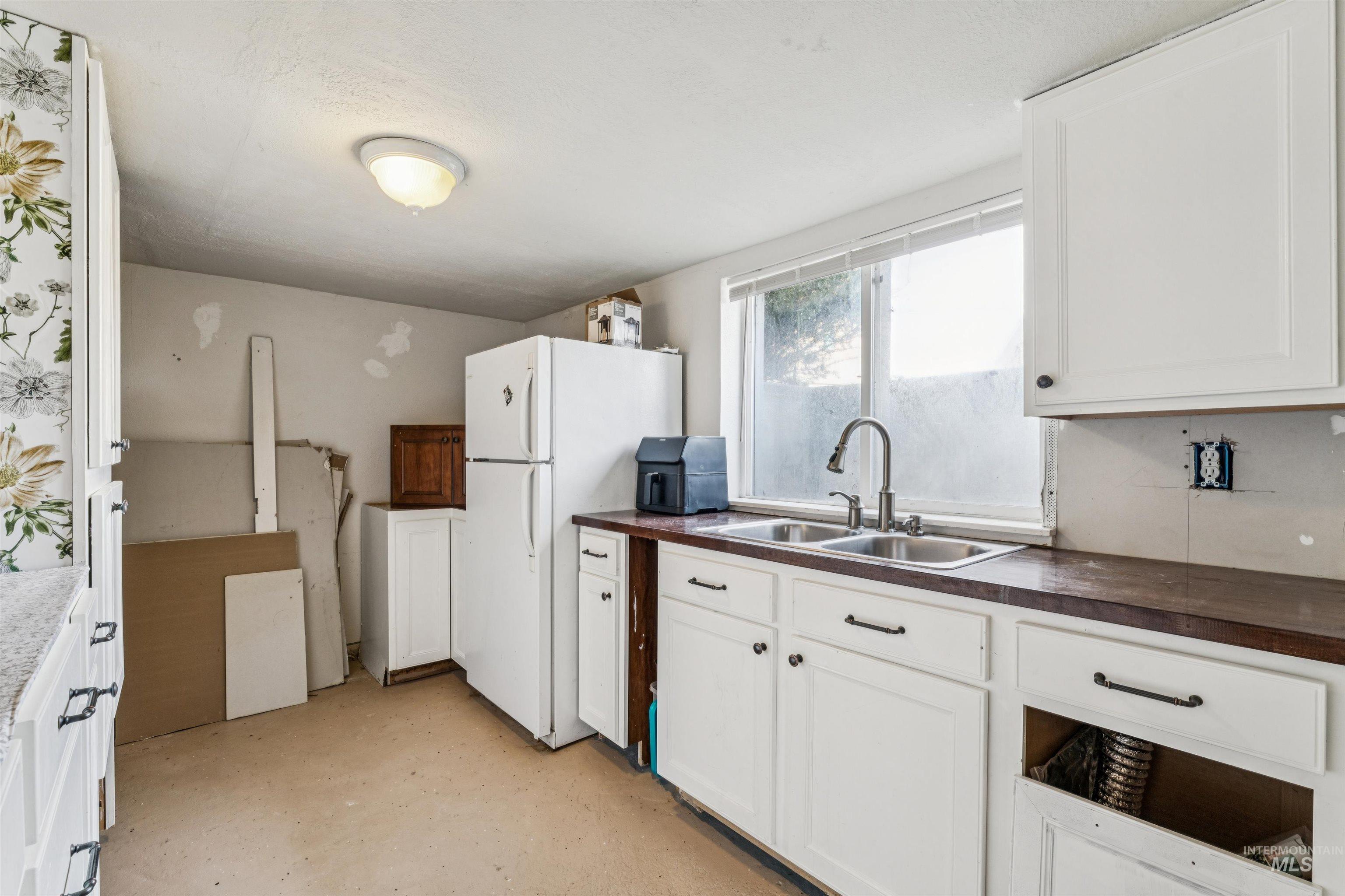 124 Halstead Street Caldwell, ID 83605 - Photo 21 of 42 Kitchen featuring freestanding refrigerator, concrete floors, and white cabinetry