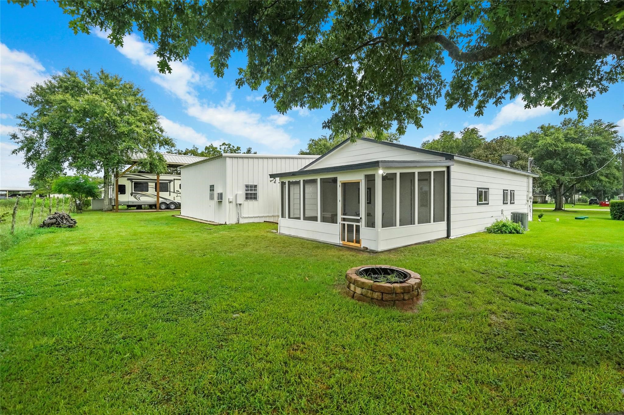 30720 Waller Spring Creek Road Waller, TX 77484 - Photo 3 of 22 Spacious back-of-property view featuring a screened patio, 2-car garage, well house, and covered RV parking with hookups.