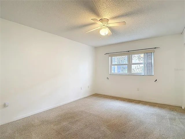 an empty room with windows and fan
