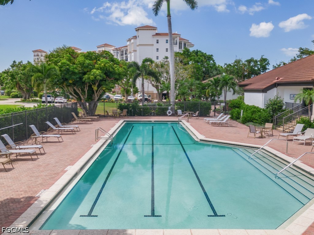 232 La Peninsula Boulevard, Unit 232 Naples, FL 34113 - Photo 39 of 44 a view of swimming pool with seating area and trees in the background