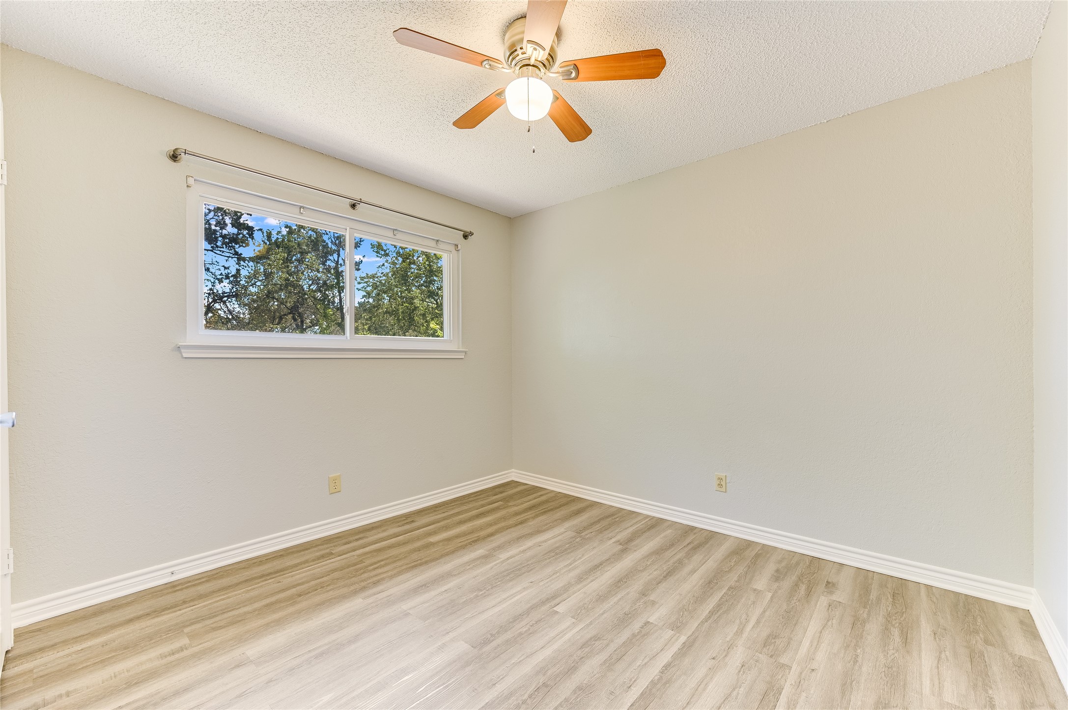 526 Cutty Trail, Unit B Lakeway, TX 78734 - Photo 10 of 10 Light-filled interior featuring wood-finish flooring, a ceiling fan with light fixture, white baseboards, and a window with white trim
