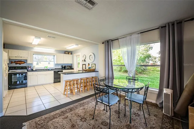 a kitchen with stainless steel appliances granite countertop a stove a refrigerator a kitchen island a table and chairs in it