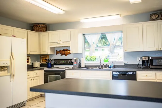 a kitchen with stainless steel appliances granite countertop a stove a sink a microwave and cabinets