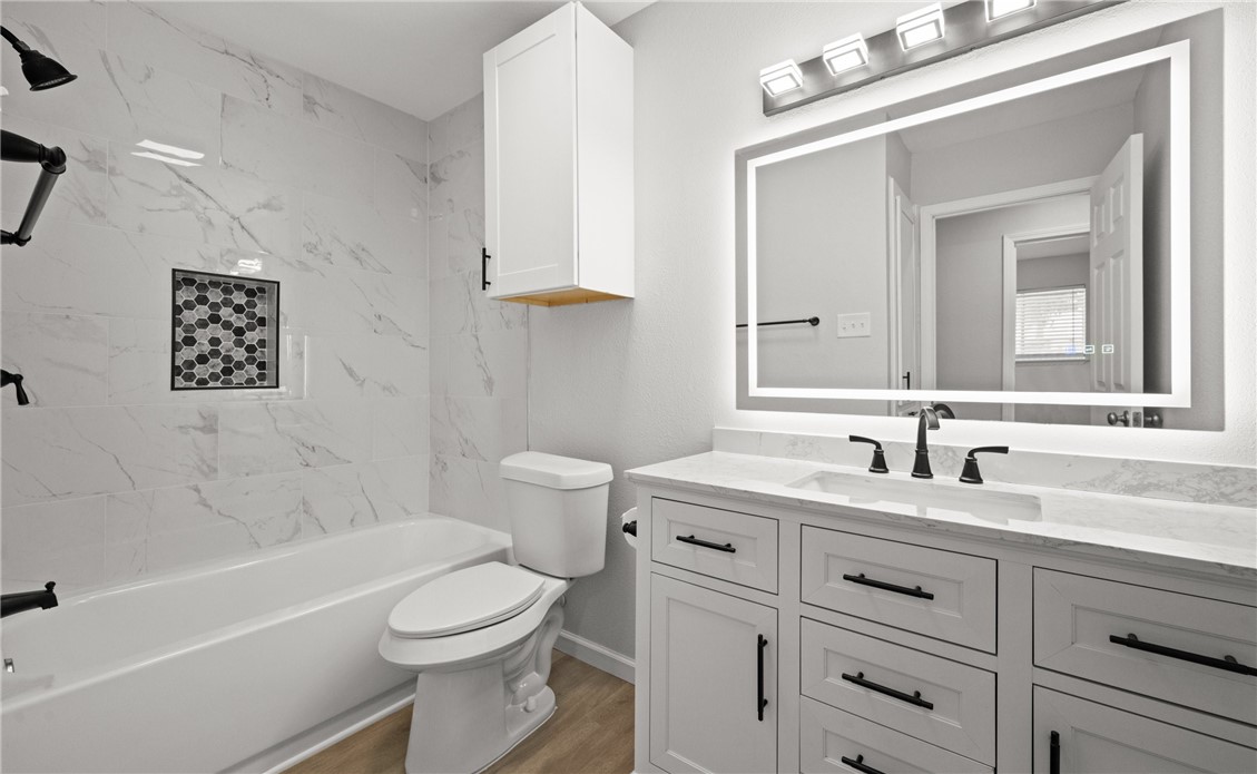 1021 Espana Drive Portland, TX 78374 - Photo 6 of 10 a bathroom with a toilet a sink a mirror a bathtub and vanity