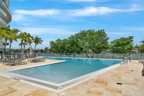 a view of a swimming pool with a lawn chairs under an umbrella