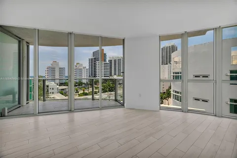 a view of an empty room with wooden floor and windows