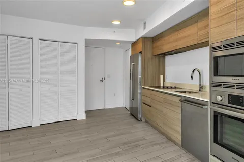 a kitchen with stainless steel appliances granite countertop a sink and cabinets with wooden floor