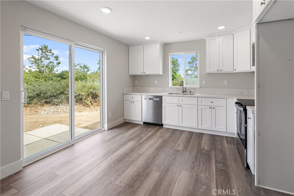 6018 William Street Riverside, CA 92504 - Photo 40 of 59 a kitchen with stainless steel appliances granite countertop a stove a sink and white cabinets with wooden floor