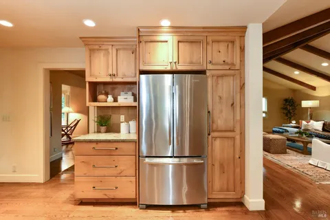 a kitchen with stainless steel appliances granite countertop a stove a sink dishwasher and a refrigerator with wooden floor