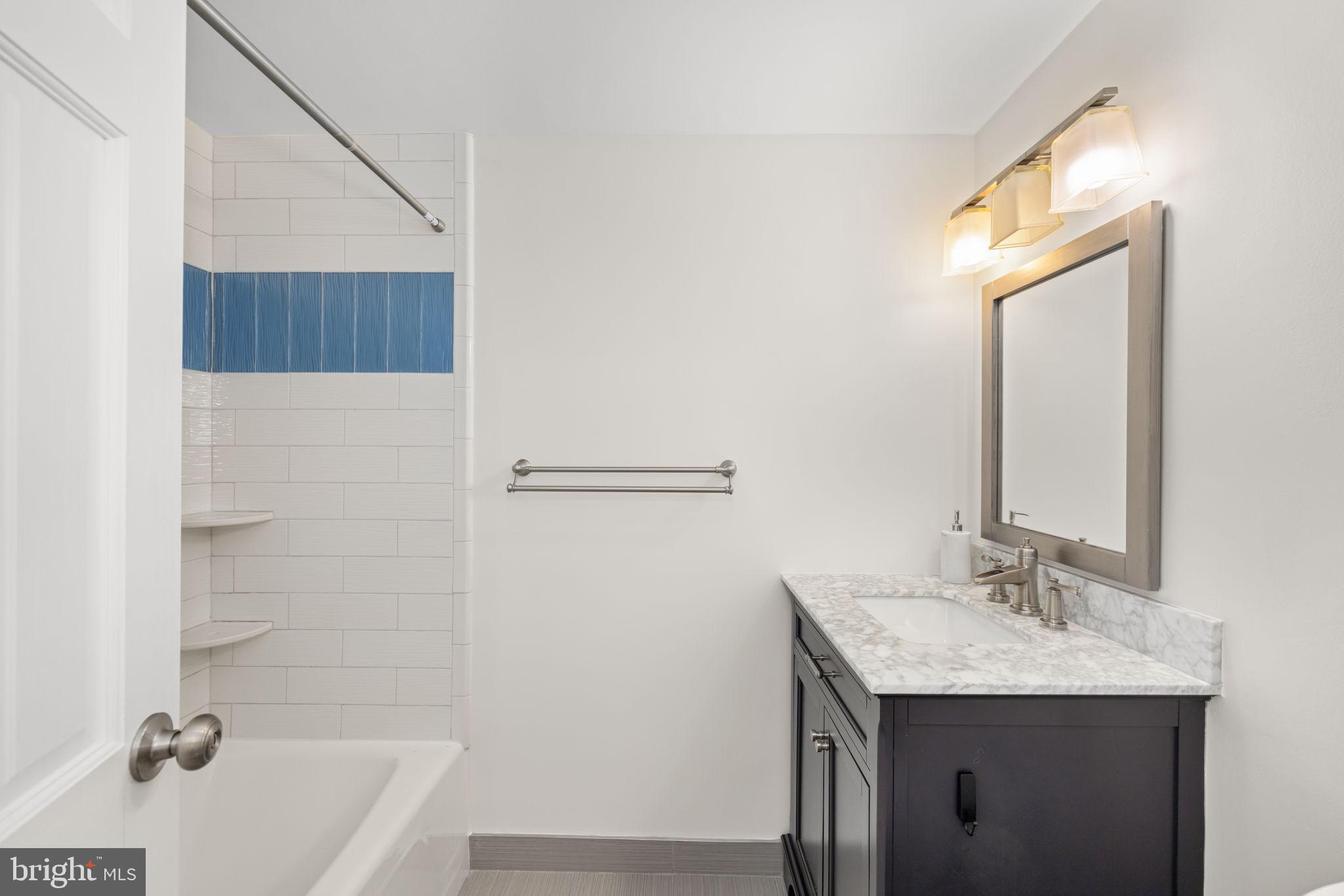 4100 Cathedral Avenue Northwest, Unit 712 Washington, DC 20016 - Photo 12 of 24 a bathroom with a granite countertop sink a mirror and a bathtub