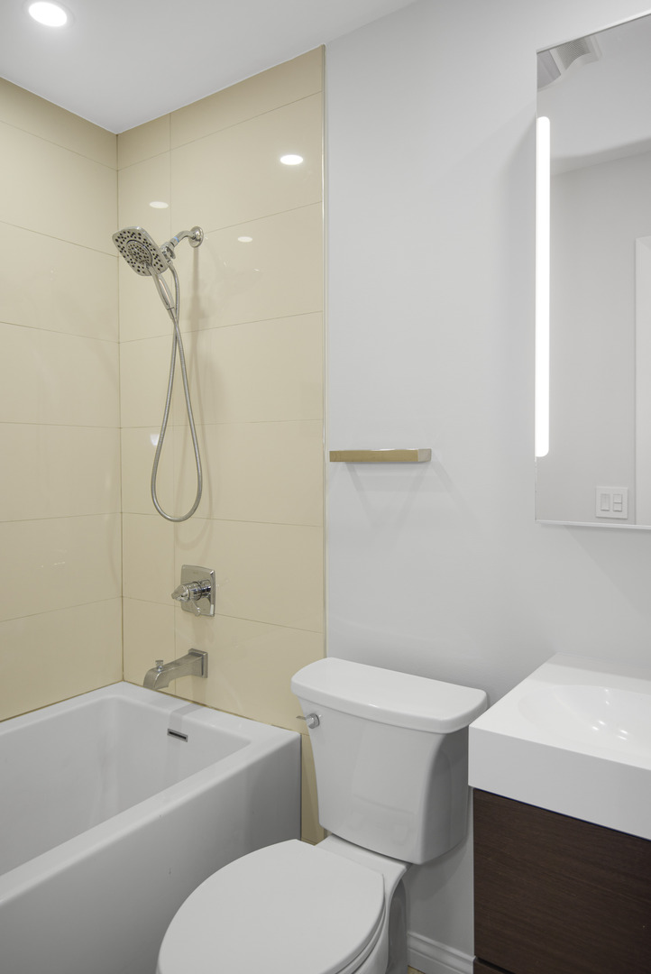 1168 Middlebury Lane, Unit A1 Wheeling, IL 60090 - Photo 21 of 28 a white toilet and tub sitting next to a bathroom sink
