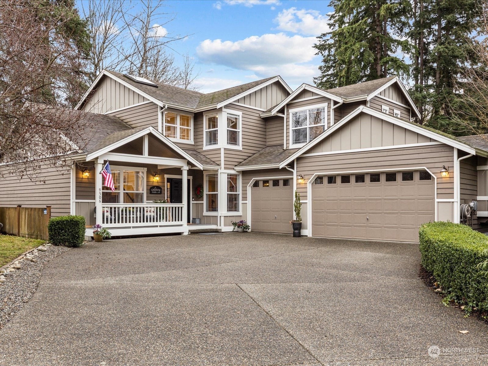 9506 Northeast 191st Street Bothell, WA 98011 - Photo 1 of 40 a view of a white house with large windows and a yard with plants and large trees