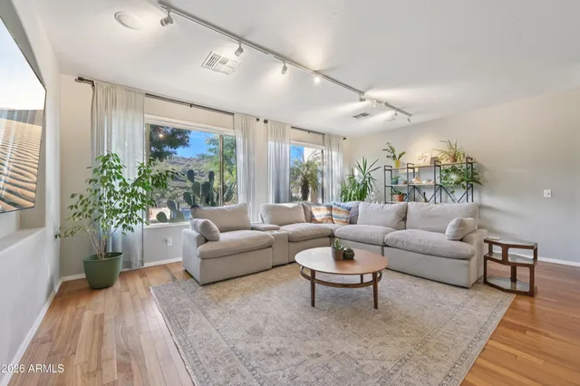 a kitchen with stainless steel appliances granite countertop a refrigerator a sink dishwasher a dining table and chairs with wooden floor