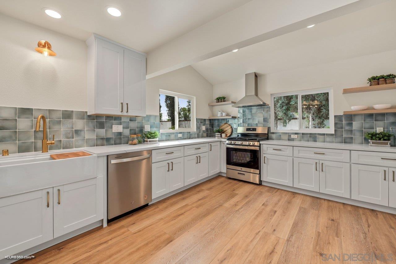 a large kitchen with a lot of white cabinets and wooden floor