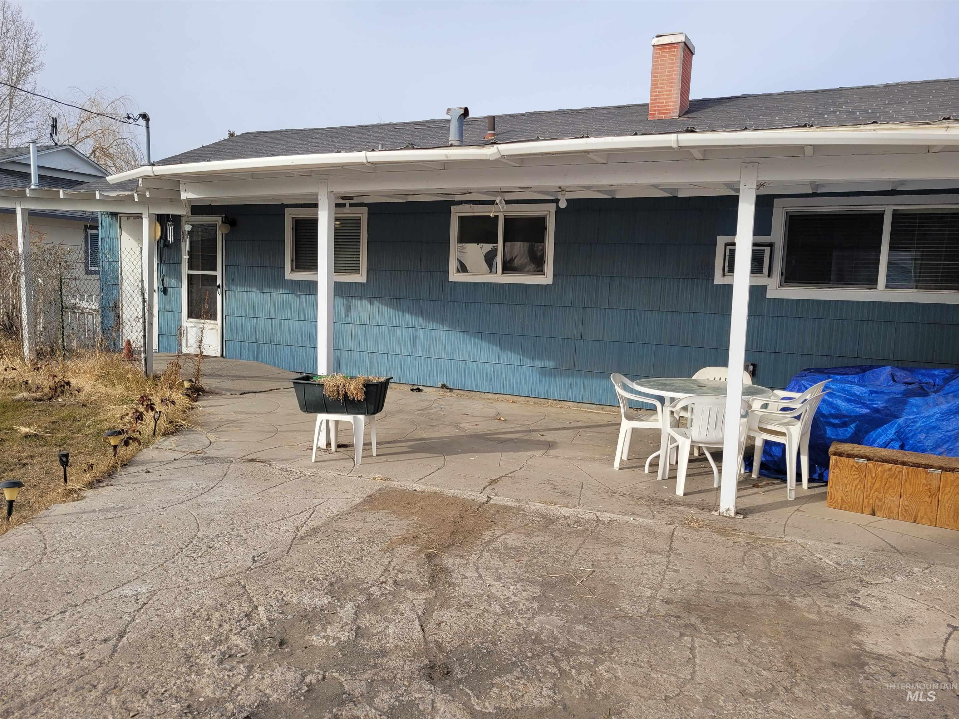 401 South 4th Street Rupert, ID 83350 - Photo 4 of 19 Rear view of house featuring outdoor dining space, a chimney, a patio area, and a shingled roof