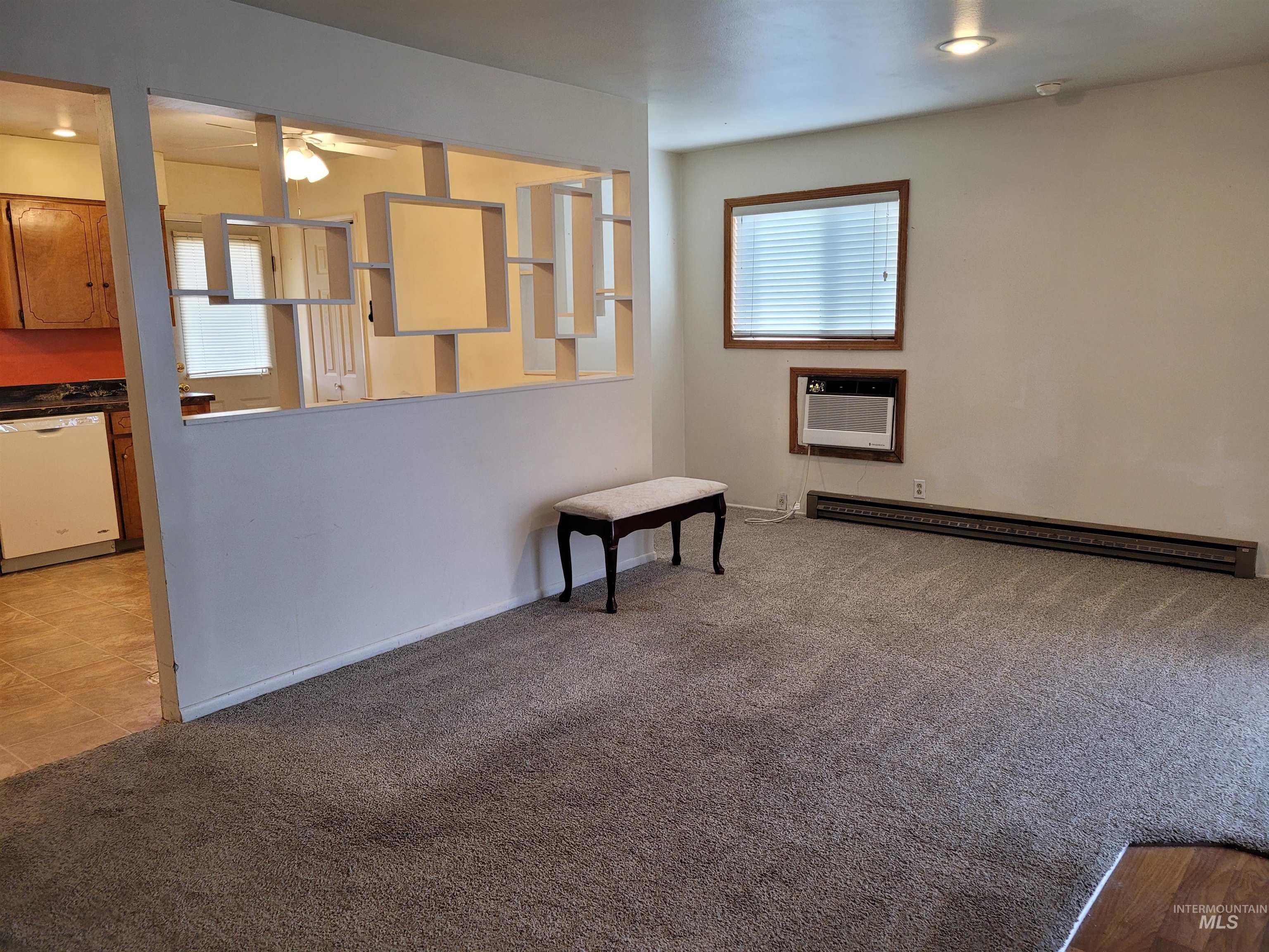 401 South 4th Street Rupert, ID 83350 - Photo 8 of 19 Unfurnished living room with light colored carpet, a baseboard radiator, a wall mounted AC, and ceiling fan