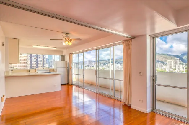 a view of an empty room with wooden floor and a window