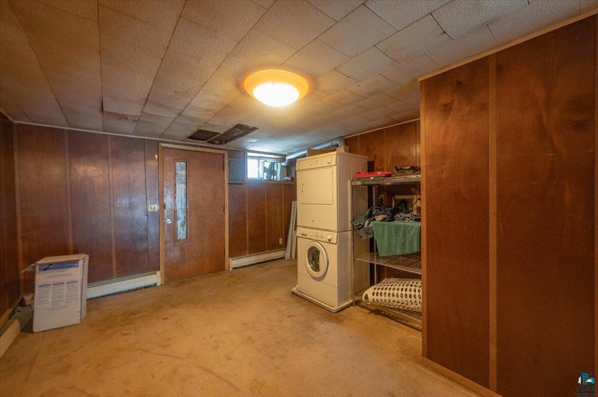 1717 Winter Street Superior, WI 54880 - Photo 12 of 15 Bedroom on upper level featuring stacked washing machine and dryer, baseboard heating, and wood walls