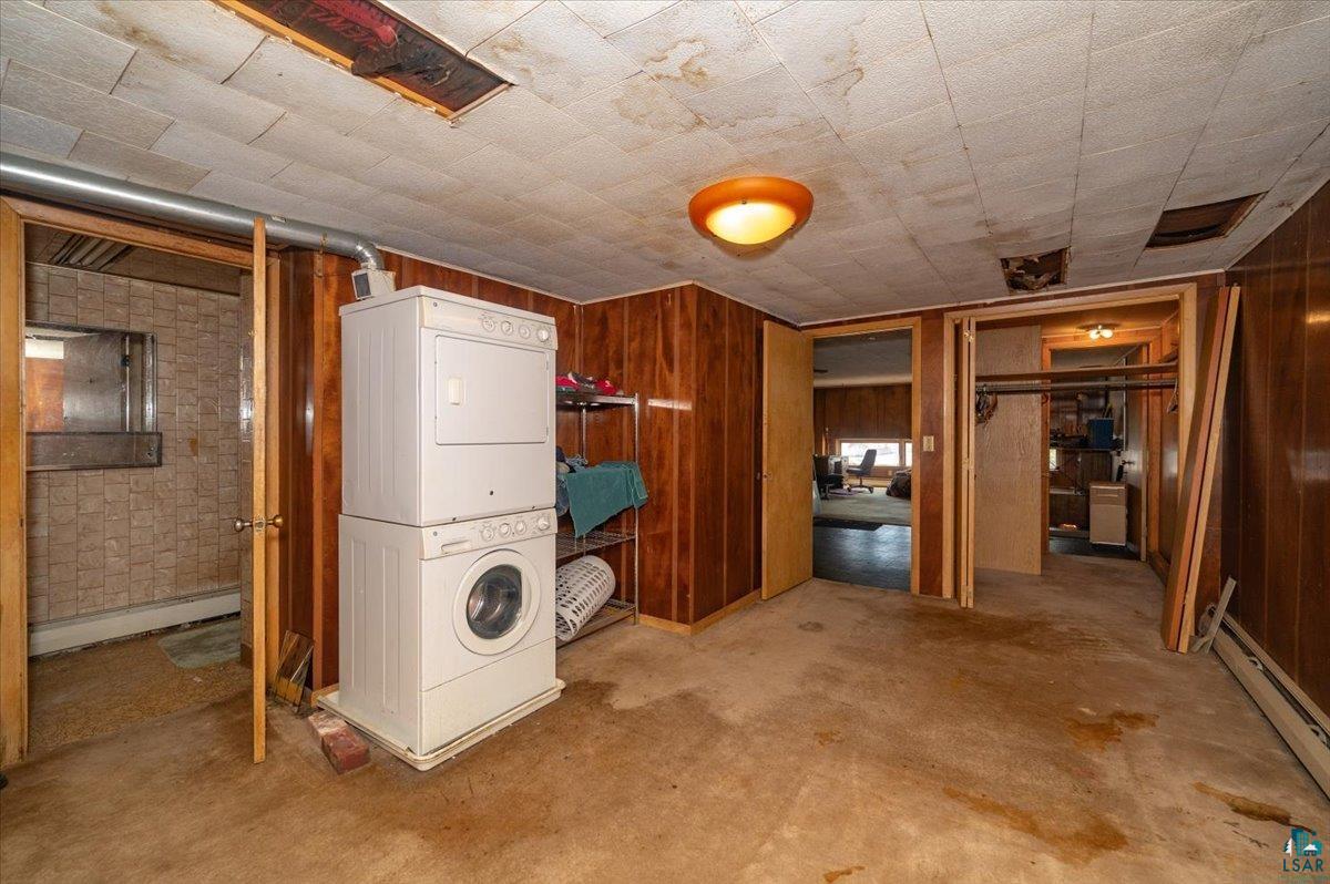 1717 Winter Street Superior, WI 54880 - Photo 13 of 15 Bedroom in upper level apartment with stacked washer and dryer, wooden walls, and a baseboard radiator