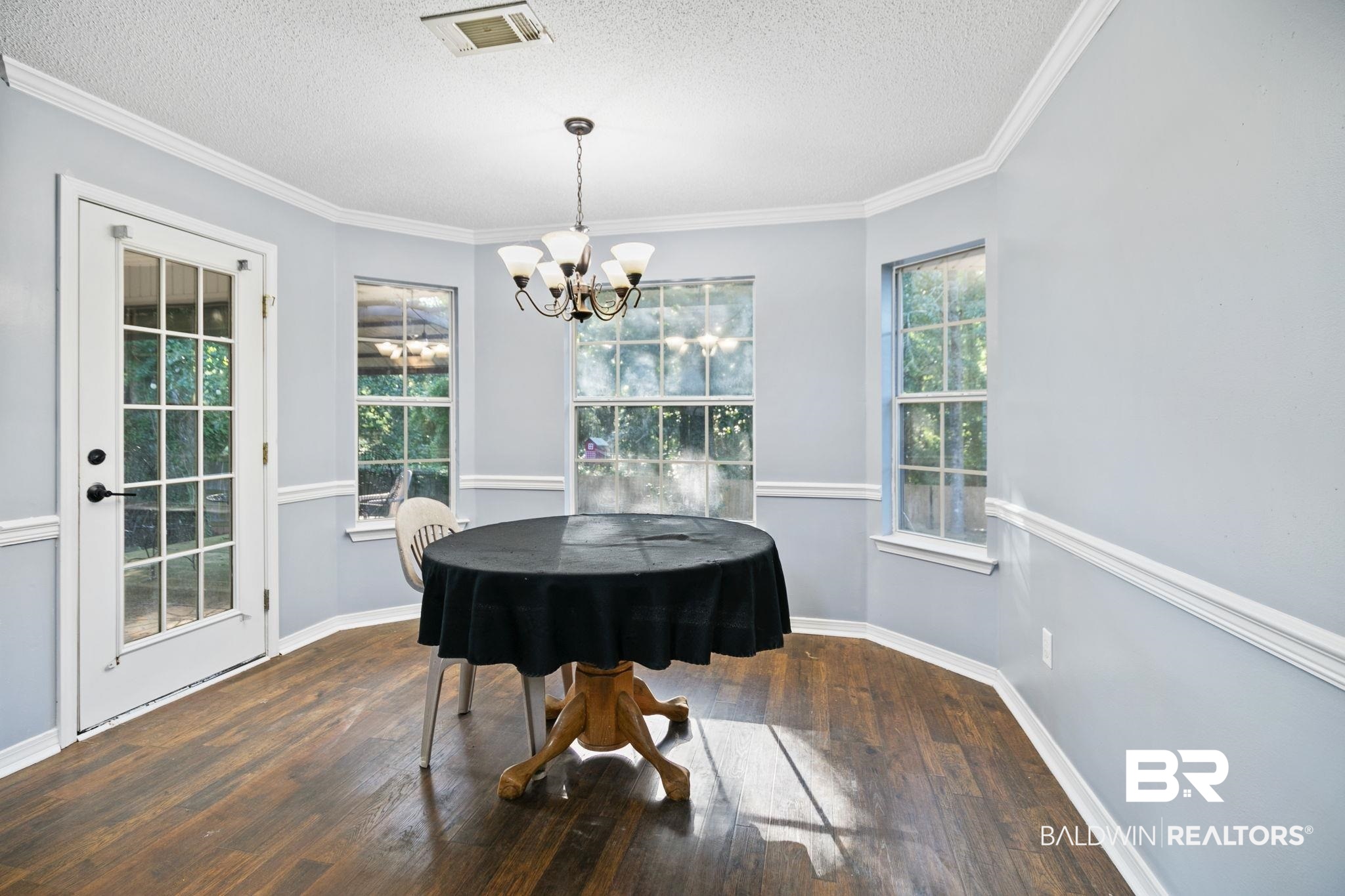 10550 Patrick Avenue Grand Bay, AL 36541 - Photo 20 of 43 Dining area with ornamental molding, dark hardwood / wood-style flooring, a textured ceiling, and a chandelier