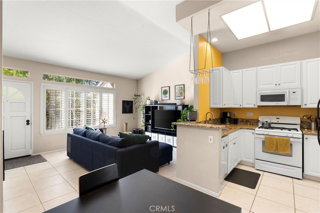 a living room with stainless steel appliances granite countertop furniture a large window and a kitchen view