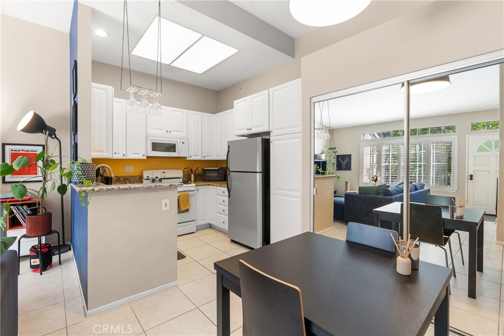 27 Castano Rancho Santa Margarita, CA 92688 - Photo 9 of 24 a kitchen with a refrigerator a stove and white cabinets with wooden floor