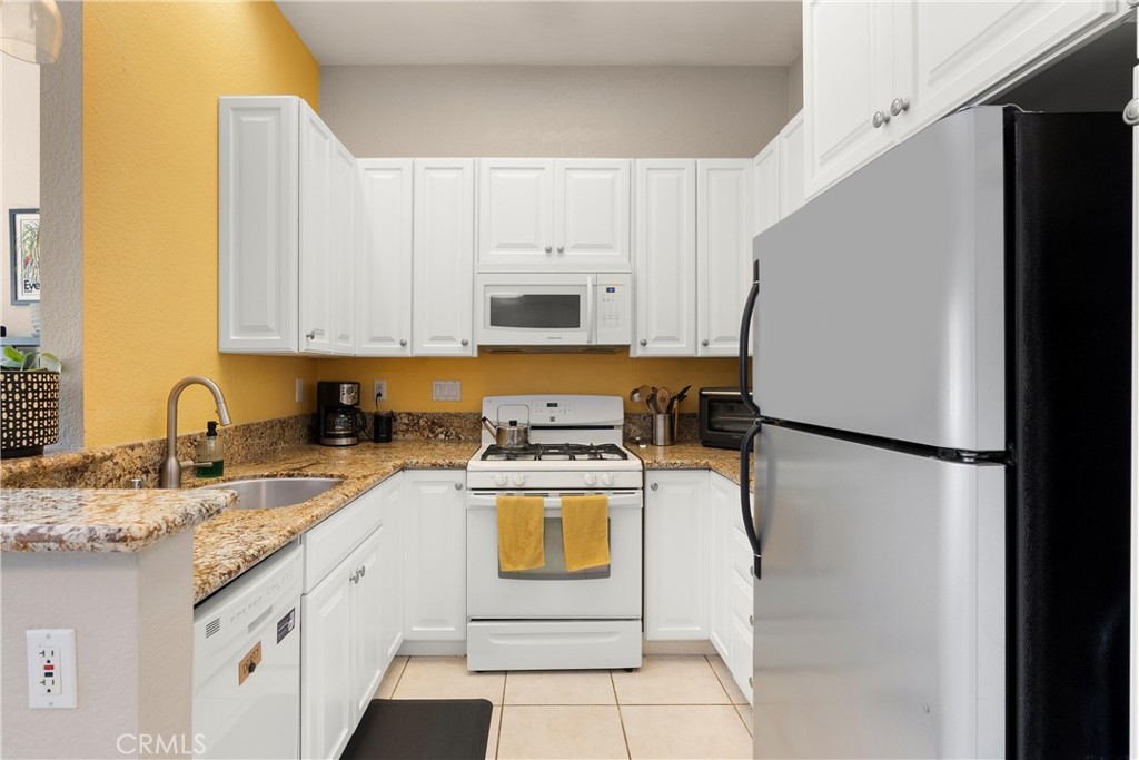 27 Castano Rancho Santa Margarita, CA 92688 - Photo 10 of 24 a kitchen with a refrigerator sink stove and white cabinets