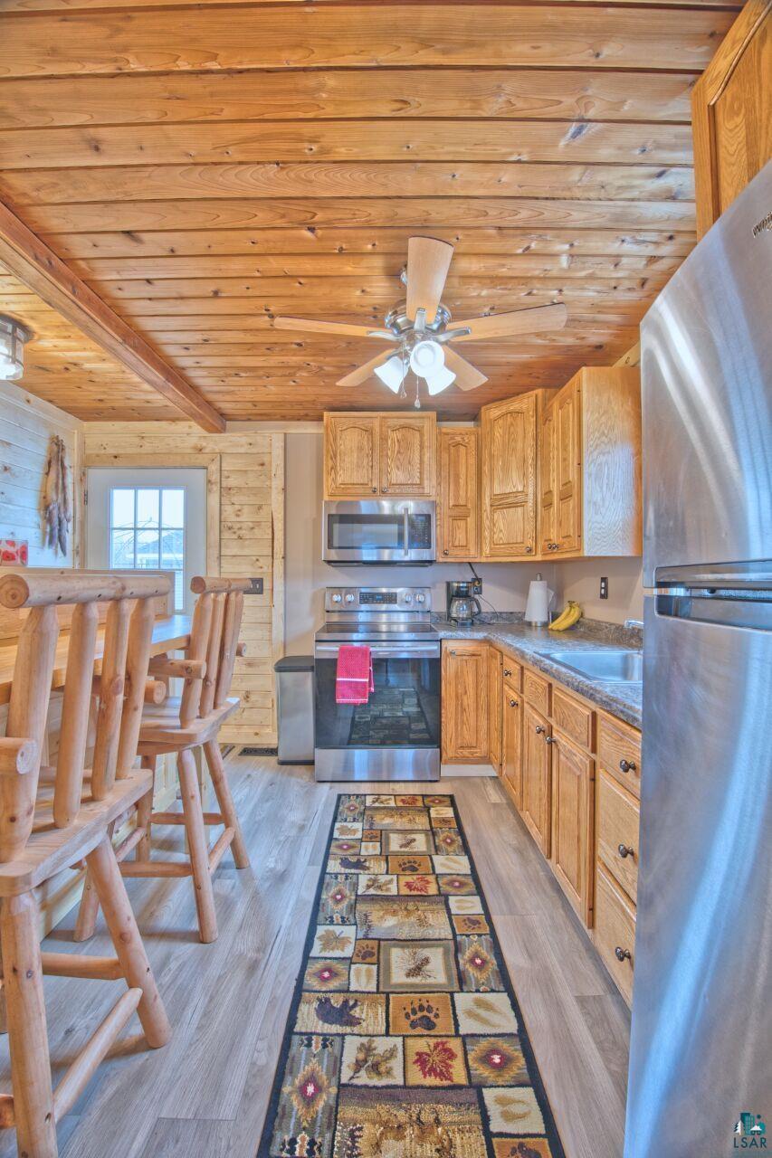 802 3rd Street Northwest Chisholm, MN 55719 - Photo 11 of 51 Kitchen with stainless steel appliances, wood ceiling, dark countertops, light wood-style flooring, and wood finish cabinets