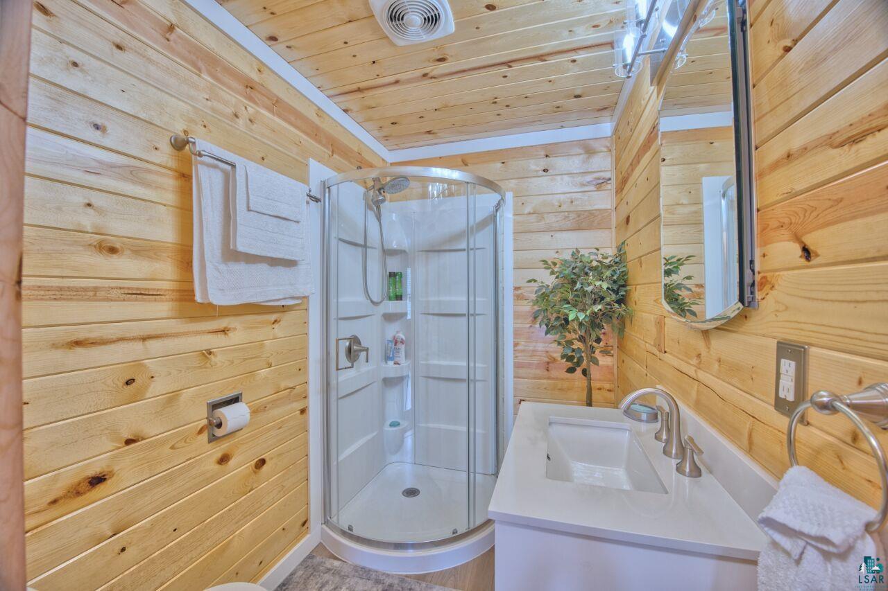 802 3rd Street Northwest Chisholm, MN 55719 - Photo 14 of 51 Bathroom with wooden walls, vanity, a stall shower, and wood ceiling