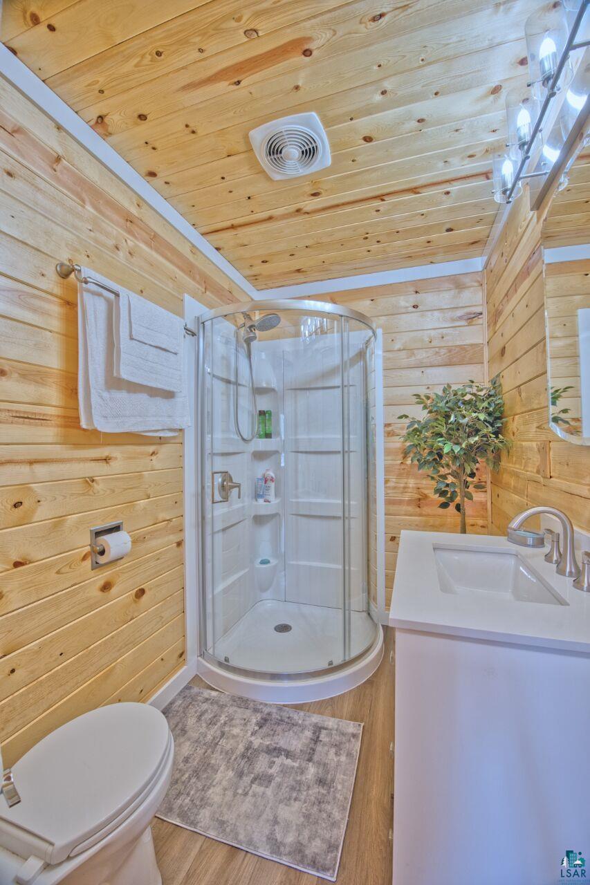 802 3rd Street Northwest Chisholm, MN 55719 - Photo 18 of 51 Full bath with wood walls, vanity, a shower stall, wooden ceiling, and light wood-style flooring
