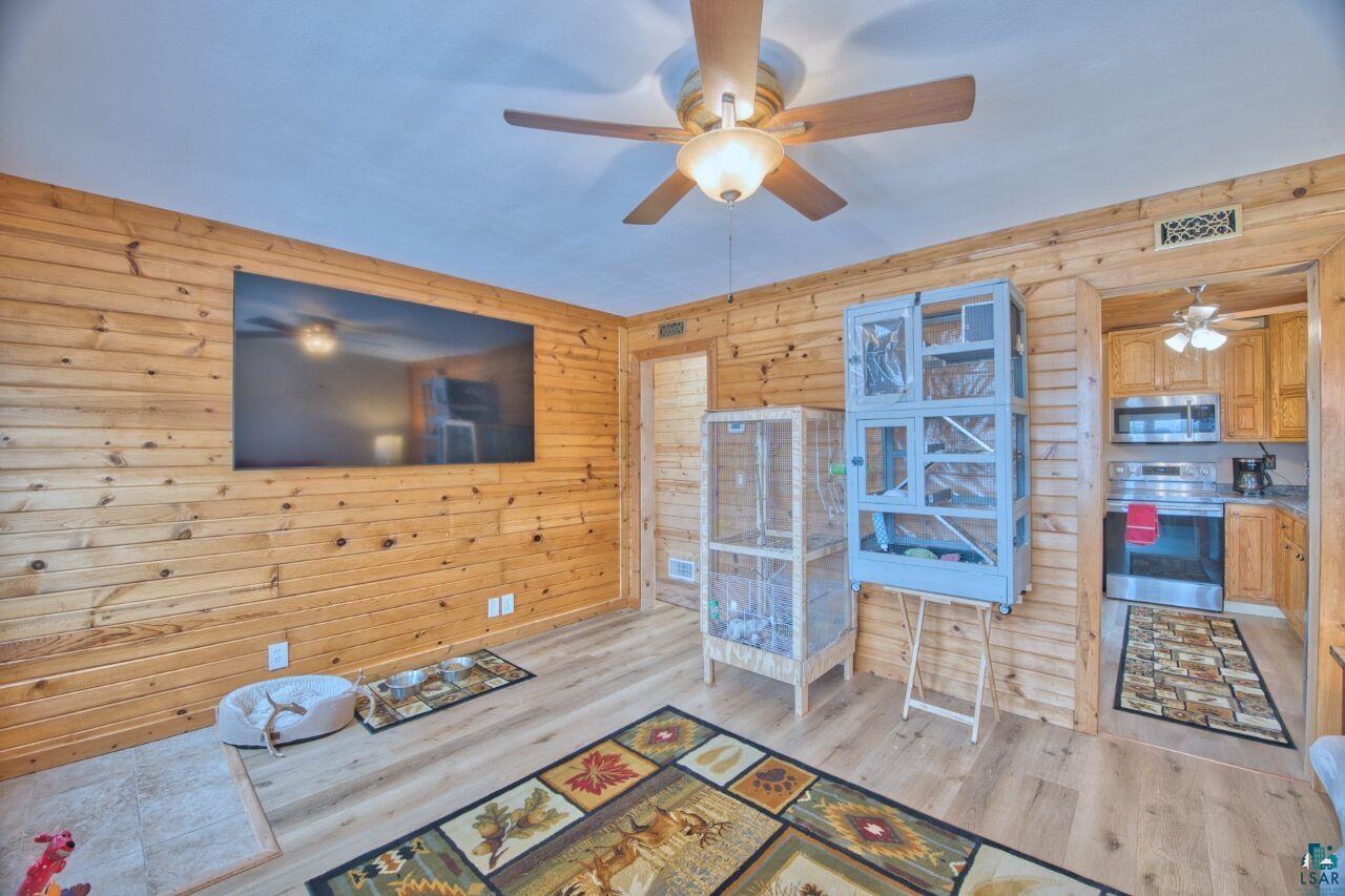 802 3rd Street Northwest Chisholm, MN 55719 - Photo 6 of 51 Living room with wood walls, light wood-style floors, and a ceiling fan