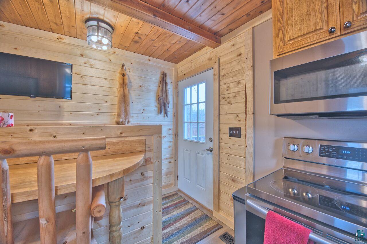 802 3rd Street Northwest Chisholm, MN 55719 - Photo 7 of 51 Kitchen with stainless steel appliances, wood walls, a wooden ceiling with exposed beams, and wood finish cabinetry