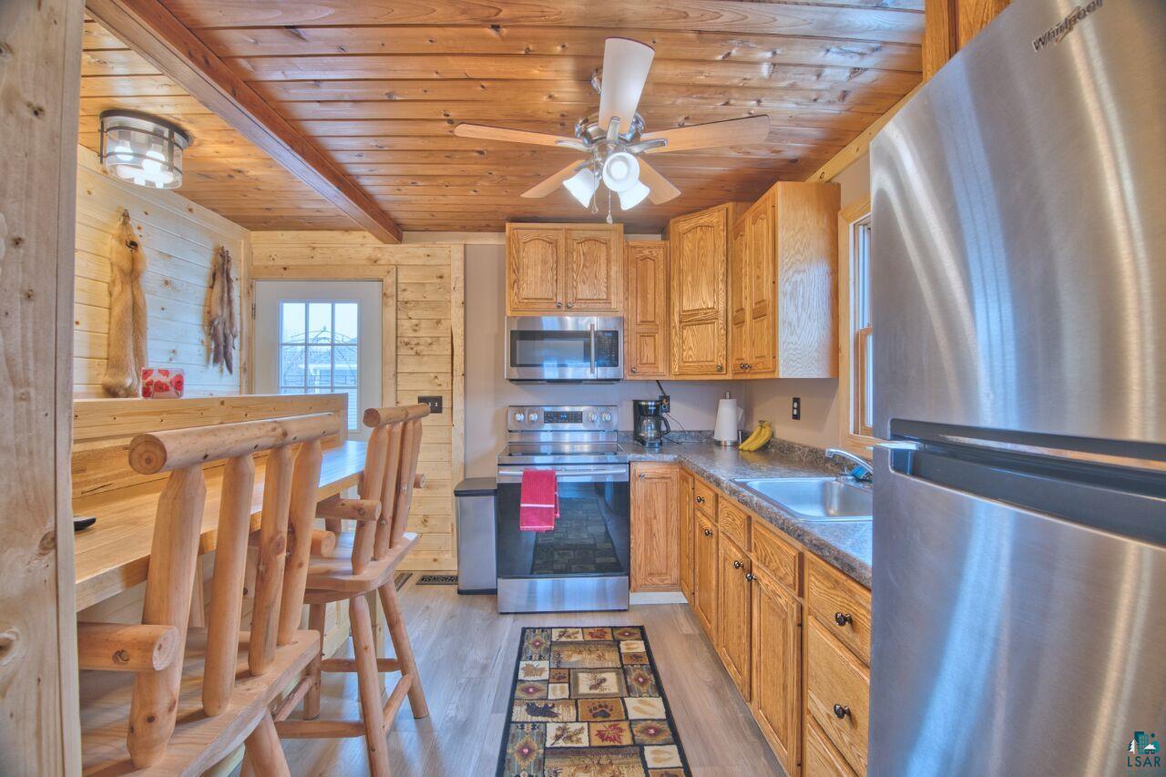 802 3rd Street Northwest Chisholm, MN 55719 - Photo 8 of 51 Kitchen with stainless steel appliances, dark countertops, light wood-style floors, ceiling fan, and wooden ceiling