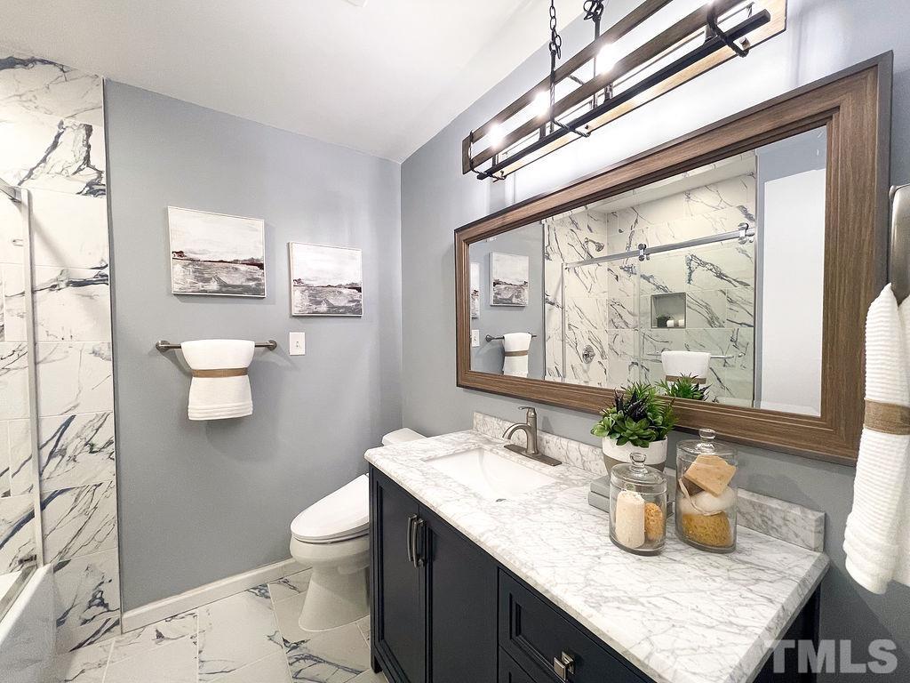 6700 Laurdane Road Raleigh, NC 27613 - Photo 13 of 25 a bathroom with a granite countertop sink a toilet a mirror and shower curtain