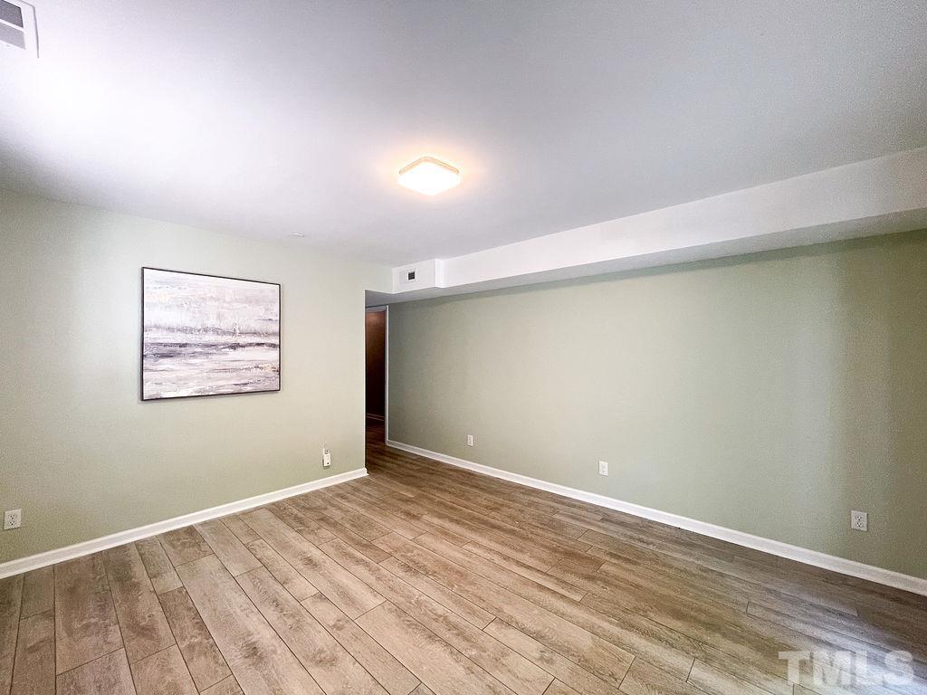 6700 Laurdane Road Raleigh, NC 27613 - Photo 21 of 25 an empty room with wooden floor and windows