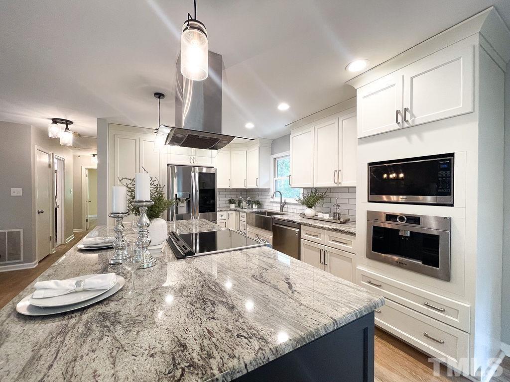 6700 Laurdane Road Raleigh, NC 27613 - Photo 4 of 25 a kitchen with kitchen island granite countertop a sink cabinets and stainless steel appliances