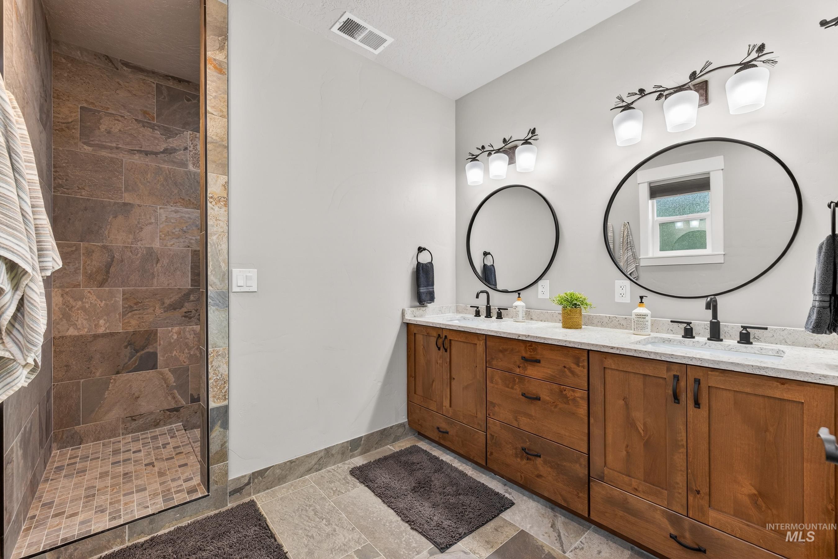 10191 Timberrim Drive Cascade, ID 83611 - Photo 27 of 44 Full bathroom featuring double vanity, a walk in shower, and stone tile flooring