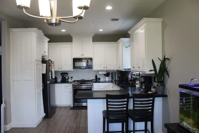 a kitchen with kitchen island granite countertop a sink cabinets and stainless steel appliances