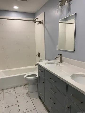 a bathroom with a double vanity sink toilet mirror and shower