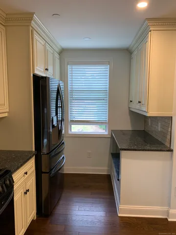 a kitchen with granite countertop a refrigerator and a stove top oven
