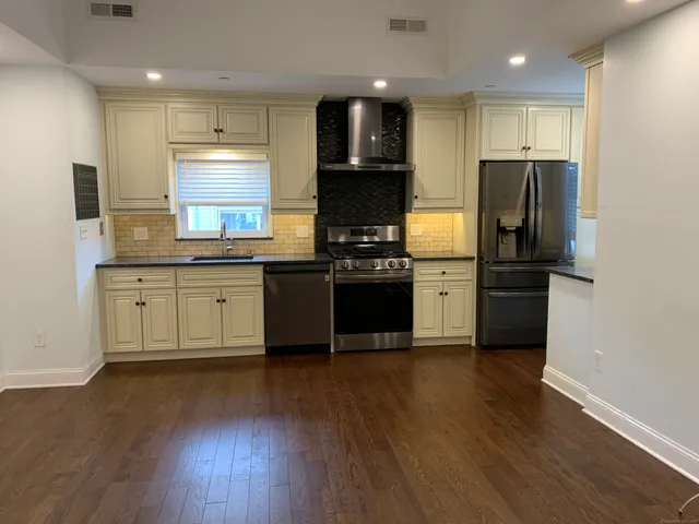 a kitchen with stainless steel appliances granite countertop a refrigerator and a stove top oven