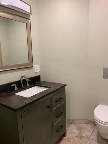 a bathroom with a granite countertop sink and a toilet