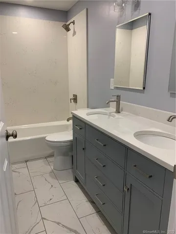 a bathroom with a granite countertop sink a toilet mirror and bathtub