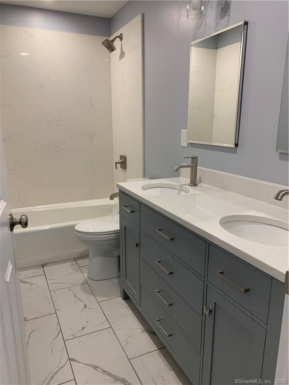 66 Cedar Street, Unit 2 Norwalk, CT 06854 - Photo 7 of 23 a bathroom with a granite countertop sink a toilet mirror and bathtub