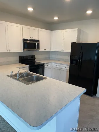a kitchen with granite countertop a refrigerator sink and white cabinets