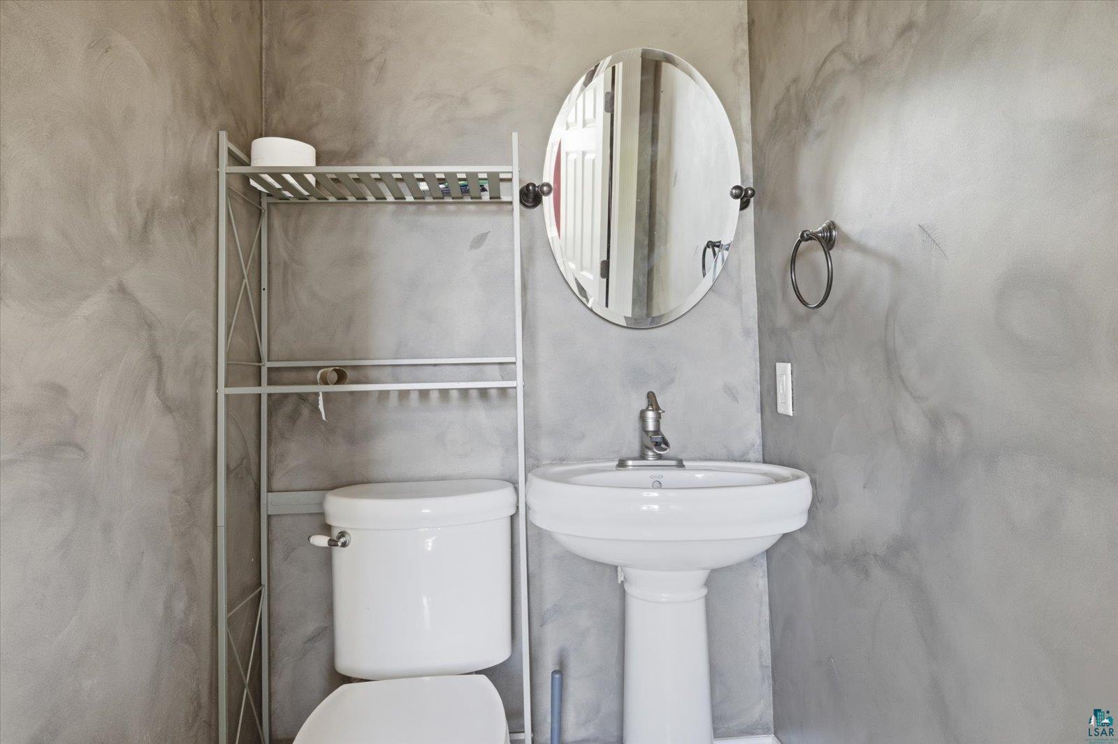 50 Main Street Soudan, MN 55782 - Photo 23 of 31 Pedestal sink with chrome faucet, complemented by an oval wall mirror