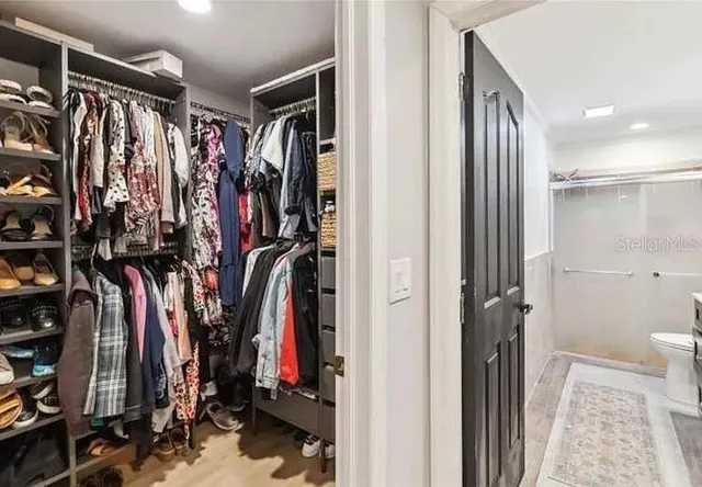a view of walk in closet with clothes and shoes