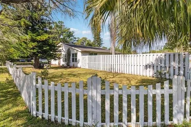a view of a white house with a large window and wooden fence