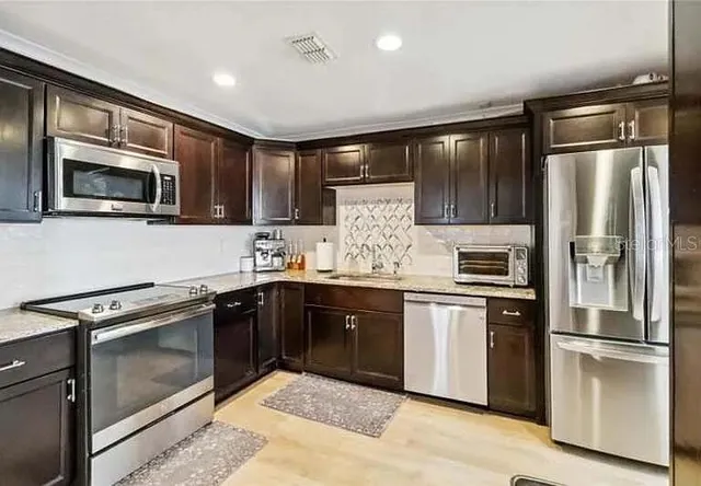 a kitchen with stainless steel appliances granite countertop a refrigerator stove and microwave