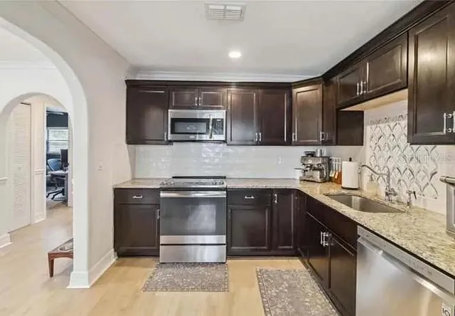 a kitchen with stainless steel appliances granite countertop a sink stove and refrigerator